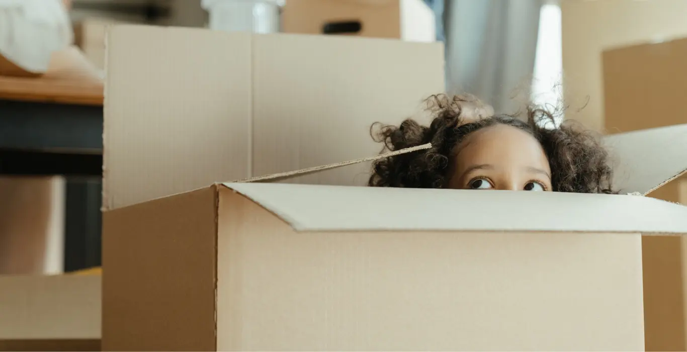 little girl peeking out of cardboard box while her parents pack for moving house after buying packaging supplies from local Eastbourne business supplies company Fieldskill