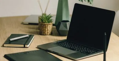 Image of a laptop on a home office desk with a notepad and pen bought from Fieldskill a local Eastbourne based stationery supplies company