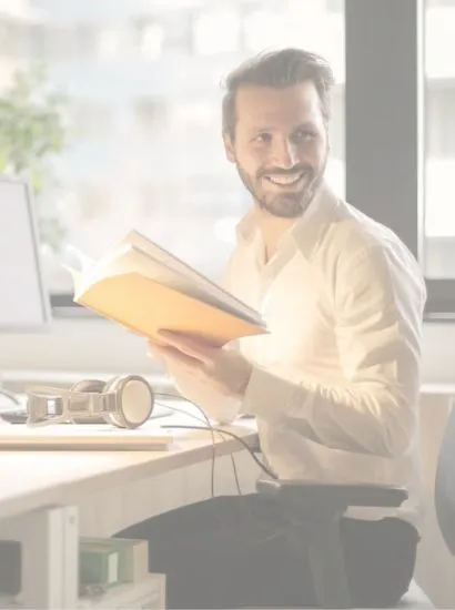 Happy office worker business owner reading book by desk after buying business supplies from local Eastbourne business Fieldskill