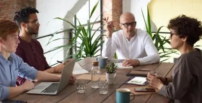 Image of a team of people in an office meeting room discussing business on meeting tables and chairs supplied by local Eastbourne based business Fieldskill